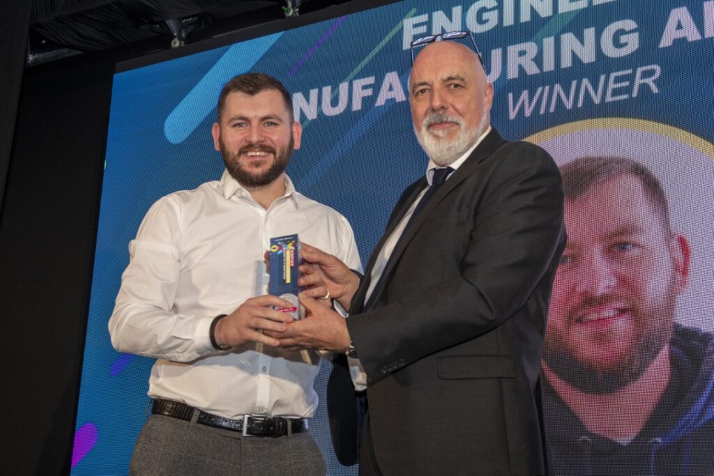 Two men holding an award on stage Two men holding an award on stage