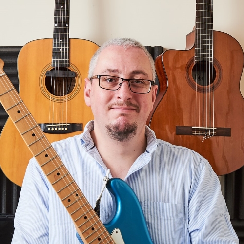 Jacob Hodge with guitars behind him