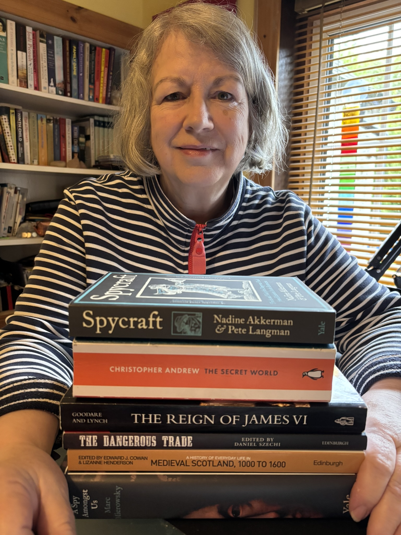 Woman seated at a table behind a pile of books