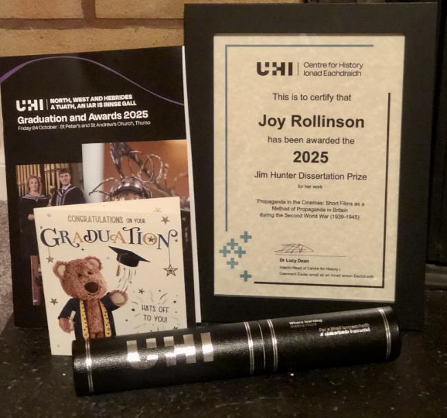 A display of the framed award certificate for the James Hunter Dissertation Prize, a degree scroll, a congratulations card and the programme for the North, West and Hebrides graduations ceremony