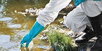 conical flask being dipped in river