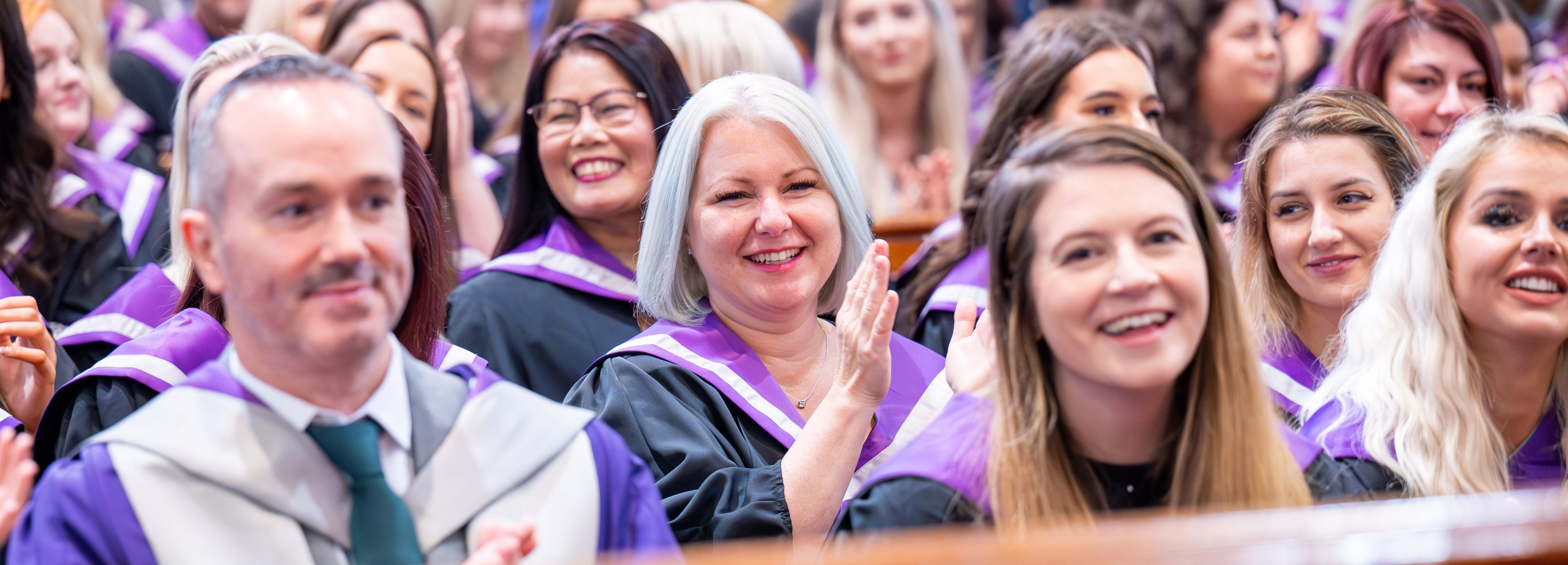 Students smiling and clapping during a graduation ceremony