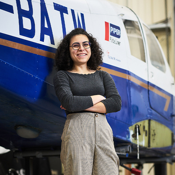 Erica smiling while leaning with her arms crossed against a plane